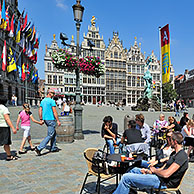 Toeristen op terrasjes op de Grote Markt met stadhuis, gildehuizen en standbeeld van Brabo te Antwerpen, België
