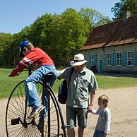 Toeristen bekijken oude fiets voor traditioneel woonhuis van Hoogstade in het openluchtmuseum Bokrijk, België
